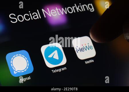 Stafford, Royaume-Uni - janvier 12 2021 : applications signal, Telegram, MeWe et doigt flou au-dessus d'elles. Les applications de réseaux sociaux gagnent en popularité aux États-Unis Banque D'Images