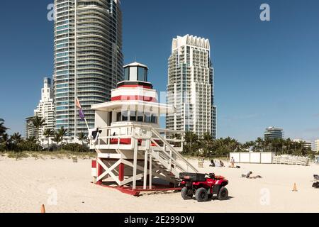 Une tour rouge et blanche de maître-nageur à rayures avec de grands condos se levant en arrière-plan, sur South Beach, Miami Beach, Floride Banque D'Images