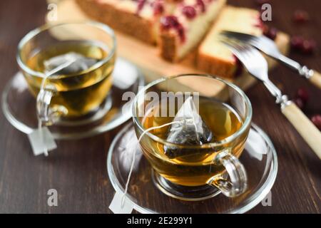 Thé vert infusé dans des sachets de thé pyramidaux dans des tasses en verre et une tarte aux baies. Priorité sélective aux boissons saines Banque D'Images