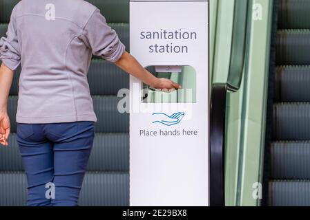 Vue rapprochée d'une femme qui se désinfecte les mains au poste d'assainissement Banque D'Images
