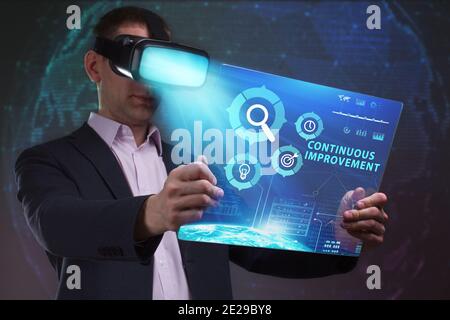 Concept commercial, technologique, Internet et réseau. Le jeune homme d'affaires travaillant dans des lunettes de réalité virtuelle voit l'inscription: Amélioration continue Banque D'Images