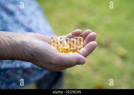 Asiatique senior vieille femme âgée tenant la vitamine E pilules médicament dans sa main, sain solide concept médical. Banque D'Images