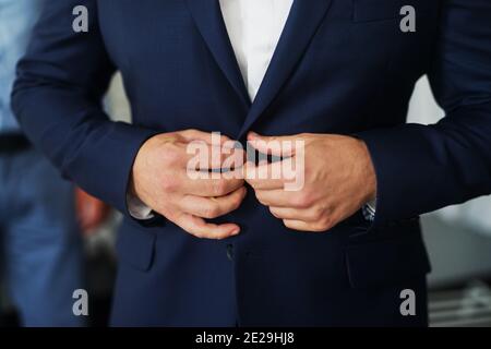 Les mains du Mans taquent un bouton sur un magnifique gilet. Banque D'Images
