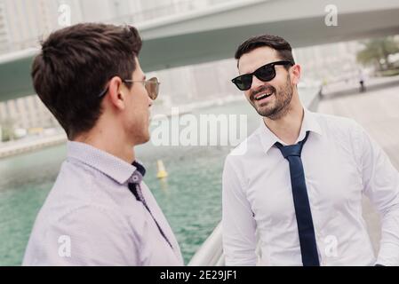 Deux jeunes hommes d'affaires modernes à Dubai Marine se sont penchés sur la clôture. Se tenir debout et discuter des affaires. Banque D'Images