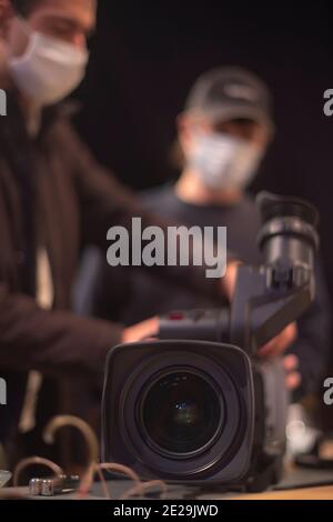 un caméraman masqué filme un spectacle télévisuel en studio. TÉLÉVISION Banque D'Images