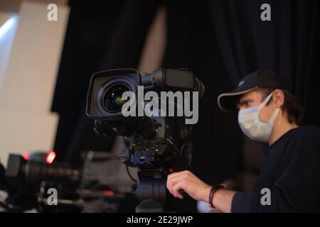 un caméraman masqué filme un spectacle télévisuel en studio. TÉLÉVISION Banque D'Images