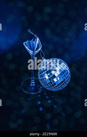 Verre de champagne cassé avec boule disco. Fête du nouvel an, anniversaire, fête des filles ou autre événement de célébration. Après la fête. Une fête créative minimaliste Banque D'Images