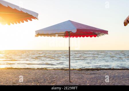 Parasol coloré sur la plage de sable vide au lever du soleil Banque D'Images