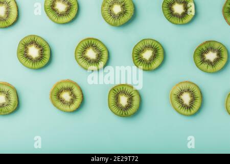 Les motifs des tranches de kiwi sur fond vert comme fond continu. Fond de fruit conceptuel texturé Banque D'Images