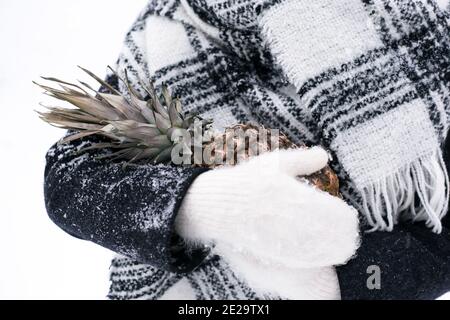 Une fille en moufles tient l'ananas en hiver Banque D'Images