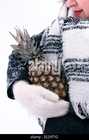 Une fille en moufles tient l'ananas en hiver Banque D'Images