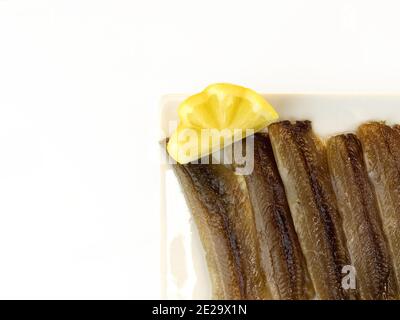 Sardines salées en conserve avec de l'huile d'olive sur une assiette avec un coin de citron Banque D'Images