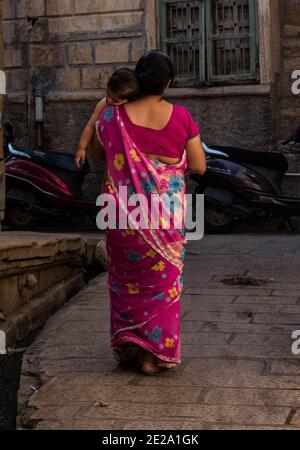 Jaisalmer, Rajasthan / Inde - octobre 30 2020 : une femme indienne d'Asie aimante marche avec son enfant endormi sur son épaule, une femme portant son sommeil Banque D'Images