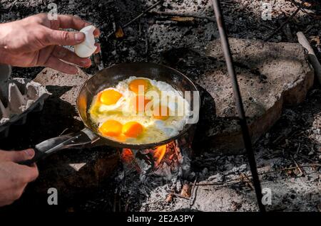 Petit déjeuner dans les bois. Œuf cuit par les mains des hommes sur un feu dans les bois Banque D'Images