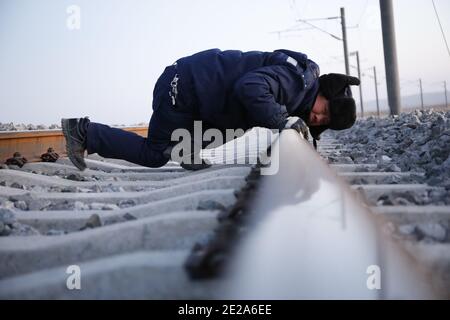 (210113) -- AKSAY, 13 janvier 2021 (Xinhua) -- UN travailleur ferroviaire entretient le chemin de fer Dunhuang dans le comté autonome de Kazak, dans la province de Gansu, dans le nord-ouest de la Chine, 12 janvier 2021. Le chemin de fer de Dunhuang, qui a ouvert ses portes en décembre 2019, croise les chemins de fer existants, notamment le chemin de fer de Lanzhou-Qinghai, le chemin de fer de Qinghai-Tibet et le chemin de fer de Lanzhou-Xinjiang, pour former le premier réseau de chemin de fer circulaire dans la région nord-ouest. Parmi eux, la section de Yangguan à Shashangou est située à Shazaoyuan, un lieu connu pour son fort vent de travers dans le comté autonome de Kazak d'Aksay. S Banque D'Images