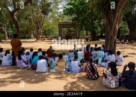 Foule de priant des bouddhistes assis devant une statue de bouddha dans une forêt. Anuradhapura, Sri Lanka. Statue de Bouddha Samadhi Banque D'Images