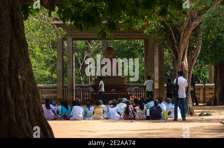 Foule de priant des bouddhistes assis devant une statue de bouddha dans une forêt. Anuradhapura, Sri Lanka. Statue de Bouddha Samadhi Banque D'Images