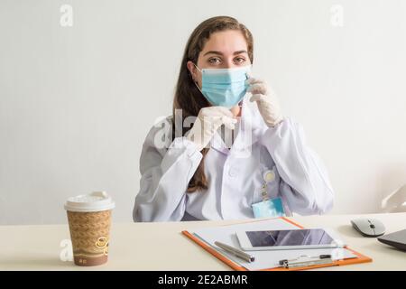 Portrait d'une femme médecin portant un masque assise sa salle de consultation Banque D'Images