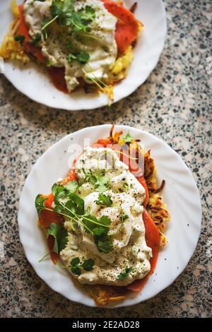 Œufs rosti royale. Crêpes de pommes de terre au saumon fumé, œufs pochés et sauce hollandaise, coriandre. Banque D'Images