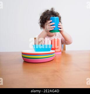 Un tout-petit joue avec des plats en plastique à une table Banque D'Images