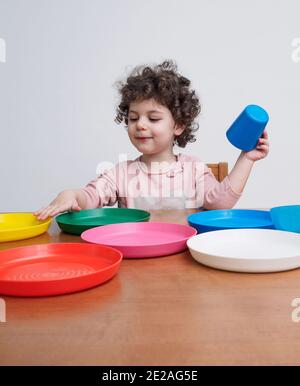 Un tout-petit joue avec des plats en plastique à une table Banque D'Images