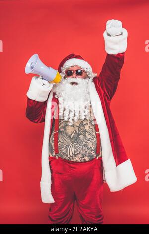 Drôle de père noël fou avec tatouage avoir du plaisir sur un arrière-plan rouge Banque D'Images