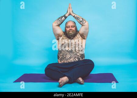 Hipster homme avec tatouages faire des exercices de yoga et de méditation dans le matin Banque D'Images