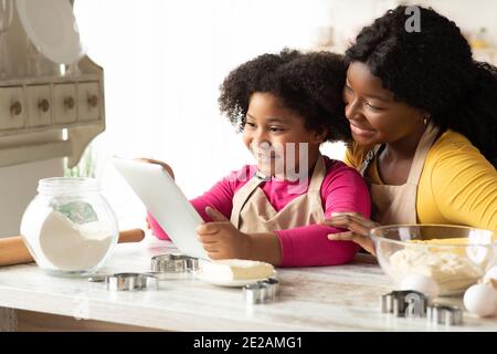 Recette de biscuits à la petite fille et à la maman noires mignonnes à vérifier Tablette numérique Banque D'Images