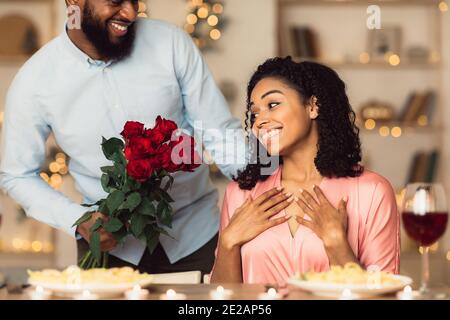 Jeune homme noir donnant des roses rouges à une femme excitée Banque D'Images