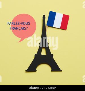 la tour eiffel, découpe sur un carton noir, le drapeau français et la question parlez-vous français écrit en français, sur fond jaune Banque D'Images