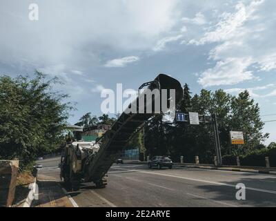 Russie, Sotchi 05.07.2020. Une fraiseuse de chaussée se trouve sur le côté de la route avec des voitures passant, des arbres verts et le ciel Banque D'Images