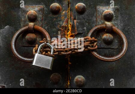 Ancienne porte en bois verrouillée avec une chaîne rouillée et un cadenas. Banque D'Images