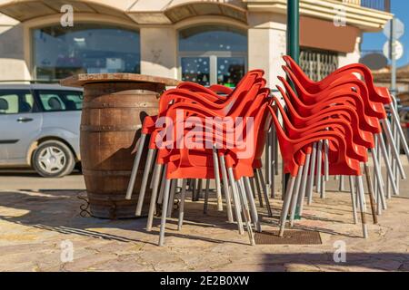 Chaises en plastique rouge empilées à l'extérieur d'une cafétéria fermée par la crise du coronavirus. Arrière-plan de l'image hors foyer. Restrictions dans la restauration Banque D'Images