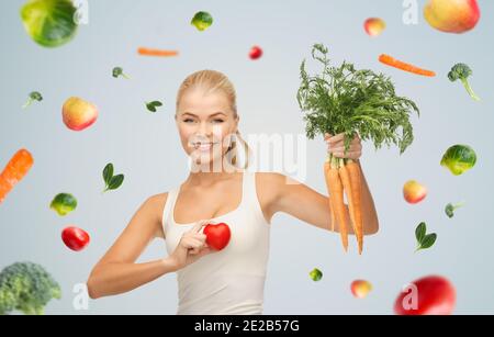 bonne jeune femme souriante avec cœur et carottes Banque D'Images