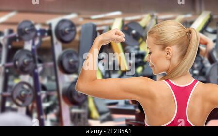 jeune femme sportive montrant son biceps en salle de sport Banque D'Images