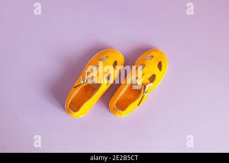 Chaussures pour bébé jaune vif sur fond lilas avec espace publicitaire. Concept de vêtements pour bébés. Banque D'Images