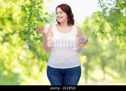 femme de taille plus qui choisit entre pomme et donut Banque D'Images