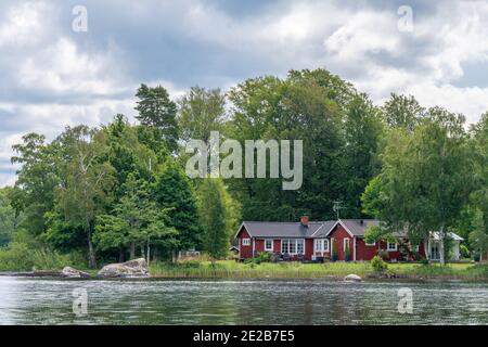 Vue sur la cabane de vacances rouge au bord d'un lac dans l'archipel de Stockholm, en Suède Banque D'Images