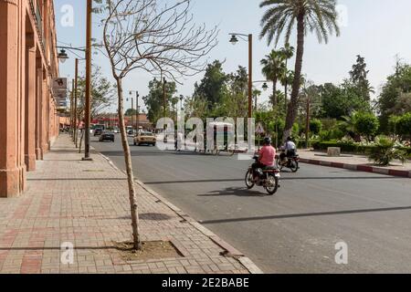 Route dans la Médina de Marrakech, au Maroc, avec des voitures, des motos et des calèches à cheval appelées calèches Banque D'Images