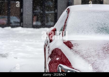 voiture rouge recouverte de neige après la tempête, gros plan, mise au point sélective, mise au point sur le miroir Banque D'Images