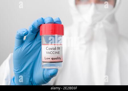 Flacon de vaccin Covid 19 dans la main des médecins. Médecin en combinaison de protection, masque facial, lunettes de sécurité et gants en caoutchouc démontrez le vaccin contre Banque D'Images