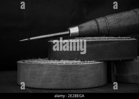 Photo en niveaux de gris d'une empeigne en bois et d'un cuir véritable roule sur une table de travail d'artisan Banque D'Images