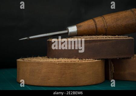 Gros plan d'une entaille en bois et d'un cuir véritable roule sur une table de travail d'artisan Banque D'Images