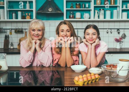Image Cinematic d'une femme âgée et de sa fille et petite-fille qui cuisinait et préparait de la nourriture dans sa belle cuisine. Grand-mère préparant des gâteaux an Banque D'Images