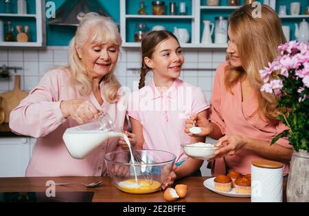 Image Cinematic d'une femme âgée et de sa fille et petite-fille qui cuisinait et préparait de la nourriture dans sa belle cuisine. Grand-mère préparant des gâteaux an Banque D'Images