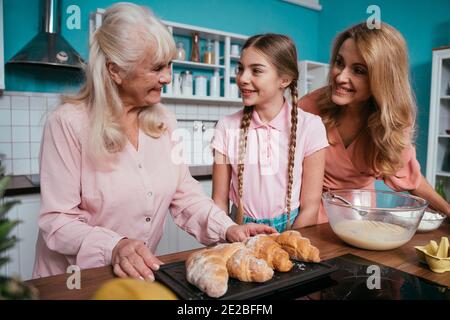 Image Cinematic d'une femme âgée et de sa fille et petite-fille qui cuisinait et préparait de la nourriture dans sa belle cuisine. Grand-mère préparant des gâteaux an Banque D'Images