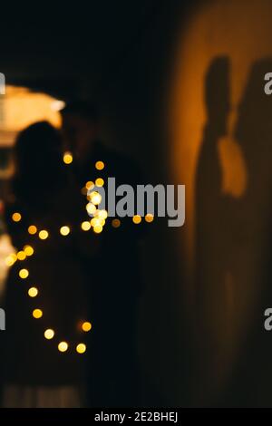 silhouettes de deux personnes - un gars et une fille, mari et femme, attaché avec une guirlande avec des lumières Banque D'Images