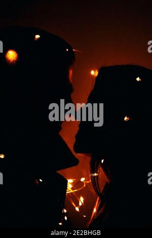 silhouettes de deux personnes - un gars et une fille, mari et femme, attaché avec une guirlande avec des lumières Banque D'Images