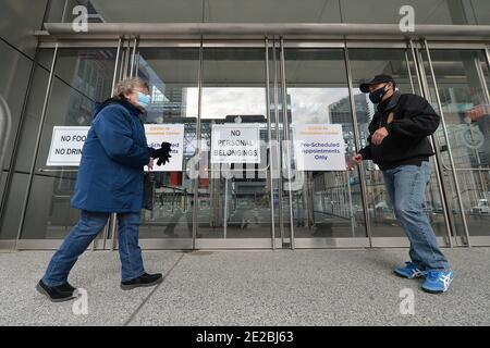 Un membre de l'équipe de sécurité aide à diriger une femme à l'intérieur du Centre de congrès Jacob K. Javits qui ouvre aujourd'hui un site de vaccination COVID-19 géré par l'État, à New York, NY, le 13 janvier 2021. Autrefois utilisé comme hôpital de traitement sur le terrain du coronavirus en mars 2020 lors de la première vague d'infections à COVID-19, le centre Jacob Javits sera maintenant utilisé pour accélérer encore la distribution des vaccins à New York; L'État de New York est actuellement en phase 1B, avec une priorité de vaccination pour les travailleurs de la santé, les personnes âgées de 65 ans et plus, les premiers intervenants, les éducateurs et les travailleurs essentiels. (Photo d'Anthony Beha Banque D'Images