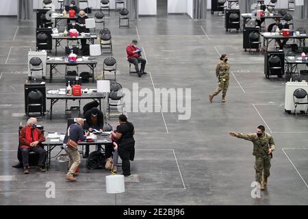 Un membre de la Garde nationale de New York (en bas à droite) dirige les personnes entrantes en tant que femme (en bas à gauche) reçoit un vaccin COVID-19 dans la zone de vaccination du Centre de congrès Jacob K. Javits qui ouvre aujourd'hui comme site de vaccination géré par l'État COVID-19, New York, NY, le 13 janvier 2021. Autrefois utilisé comme hôpital de traitement sur le terrain du coronavirus en mars 2020 lors de la première vague d'infections à COVID-19, le centre Jacob Javits sera maintenant utilisé pour accélérer encore la distribution des vaccins à New York; L'État de New York est actuellement dans la phase 1B, la vaccination étant prioritaire pour les travailleurs de la santé Banque D'Images